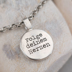 Anhänger Nugget mit Gravur "Kompass mit Herz" und "Folge deinem Herzen". Jedes Schmuckstück ist ein Unikat. Der handgefertigte Anhänger aus recyceltem Silber zeigt auf der Vorderseite einen gravierten Kompass mit Herz. Zusätzlich kannst du einen Text als Gravur auf der Rückseite wählen. Kein Anhänger gleicht exakt dem anderen und ist dein personalisiertes Unikat. Von animoART