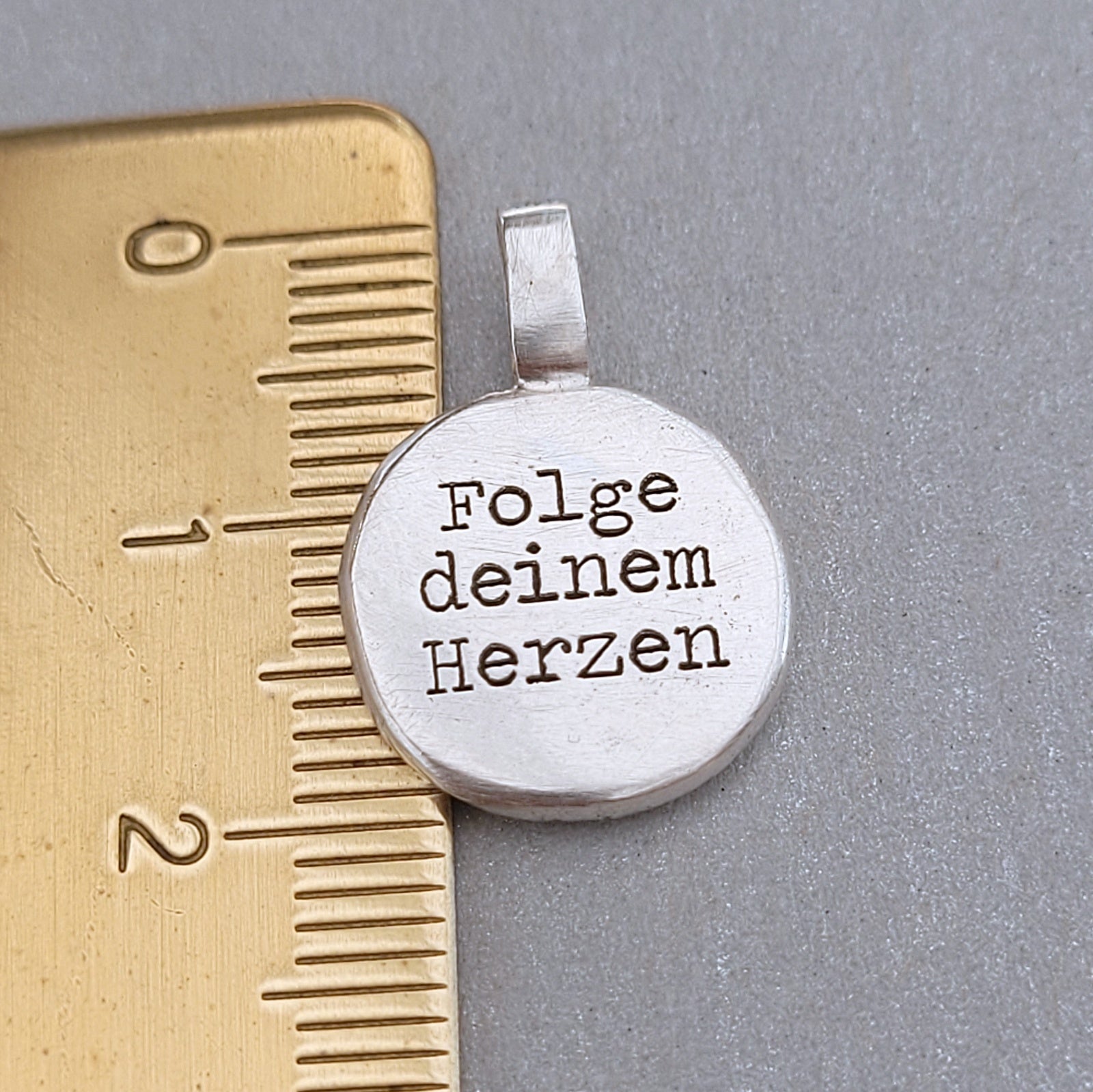 Kompass - Anhänger mit Gravur aus der Kollektion Nuggets. Motiv "Kompass mit Herz" Jedes Schmuckstück ist ein handgefertigtes Unikat. Der handgefertigte Anhänger aus recyceltem Silber zeigt auf der Vorderseite einen gravierten Kompass mit Herz. Zusätzlich kannst du einen Text als Gravur auf der Rückseite wählen. Kein Anhänger gleicht exakt dem anderen und ist dein personalisiertes Unikat.