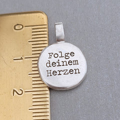 Kompass - Anhänger mit Gravur aus der Kollektion Nuggets. Motiv "Kompass mit Herz" Jedes Schmuckstück ist ein handgefertigtes Unikat. Der handgefertigte Anhänger aus recyceltem Silber zeigt auf der Vorderseite einen gravierten Kompass mit Herz. Zusätzlich kannst du einen Text als Gravur auf der Rückseite wählen. Kein Anhänger gleicht exakt dem anderen und ist dein personalisiertes Unikat.