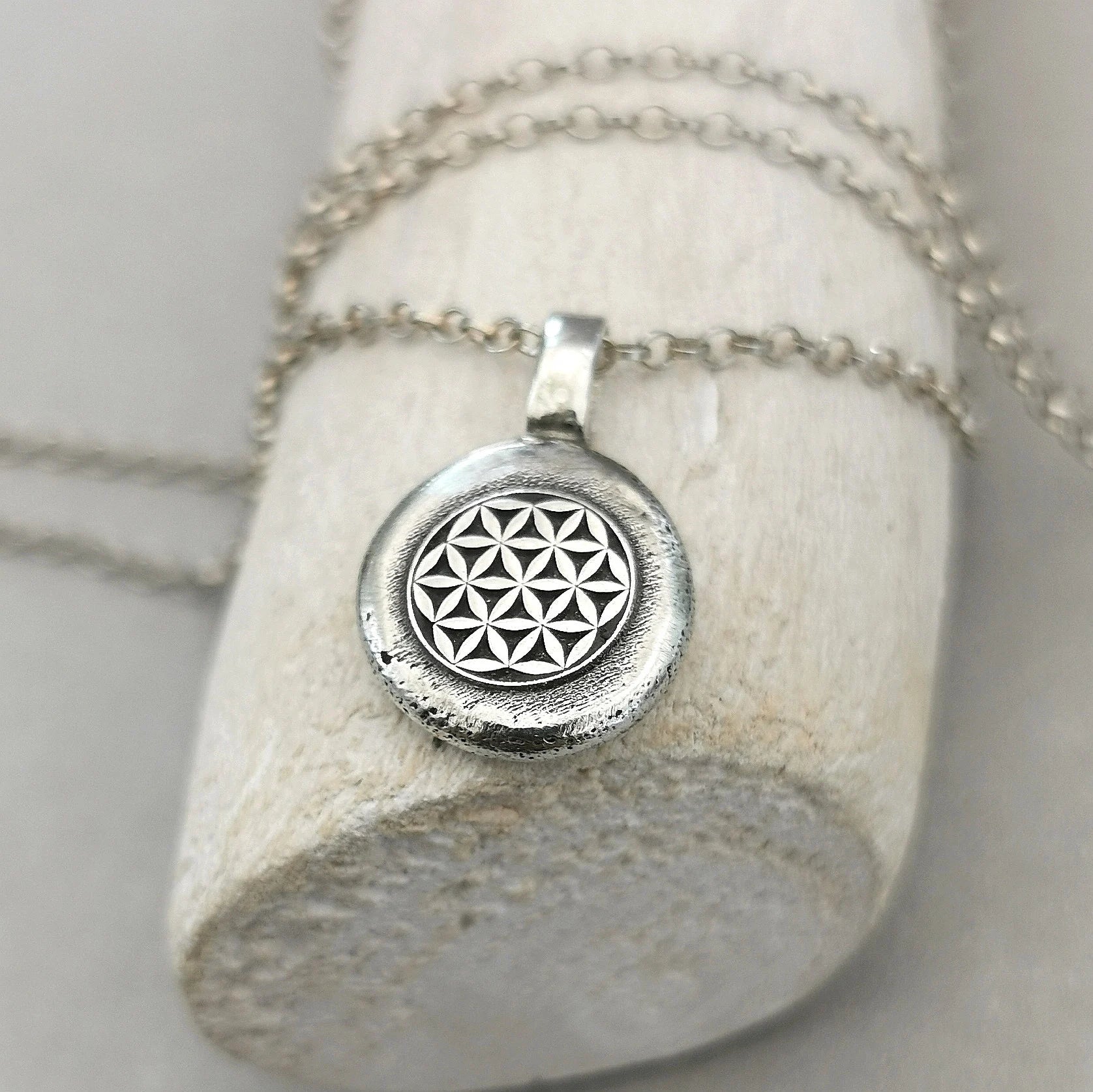 Lebensblume - Anhänger mit Gravur Aus der Kollektion Nuggets Motiv "Lebensblume" Jedes Schmuckstück ist ein handgefertigtes Unikat. Der Anhänger mit Lebensblume aus recyceltem Silber zeigt eine plastische Blume des Lebens. Kein Anhänger gleicht exakt dem anderen und jeder ist ein persönliches Unikat. Zusätzlich kannst du einen Text als Gravur für die Rückseite wählen.