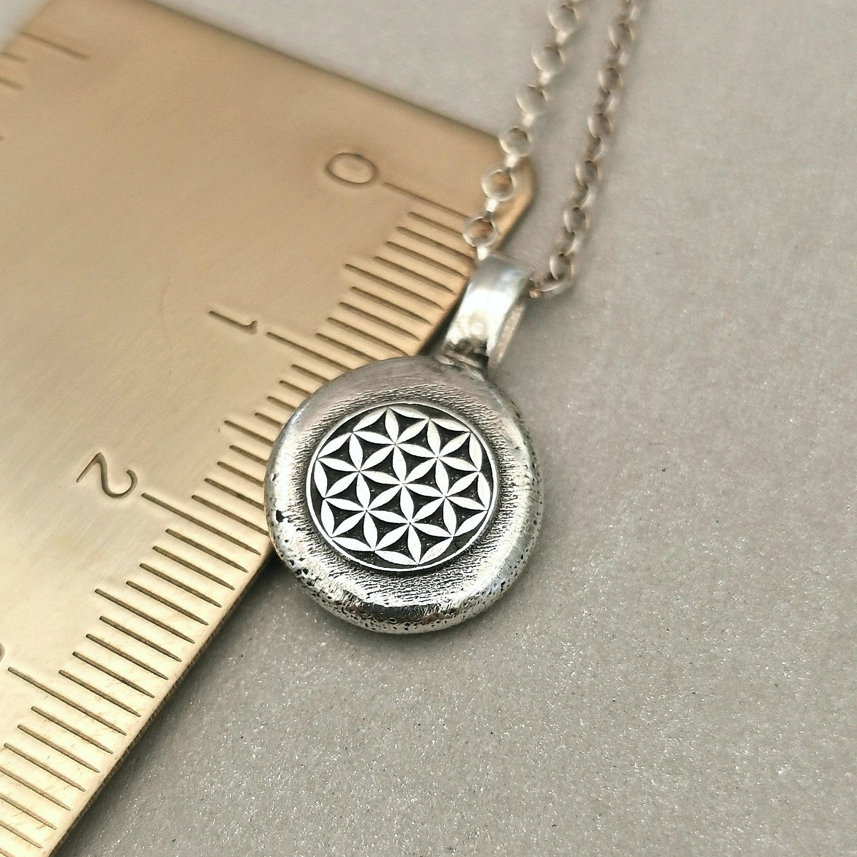 Lebensblume - Anhänger mit Gravur Aus der Kollektion Nuggets Motiv "Lebensblume" Jedes Schmuckstück ist ein handgefertigtes Unikat. Der Anhänger mit Lebensblume aus recyceltem Silber zeigt eine plastische Blume des Lebens. Kein Anhänger gleicht exakt dem anderen und jeder ist ein persönliches Unikat. Zusätzlich kannst du einen Text als Gravur für die Rückseite wählen.