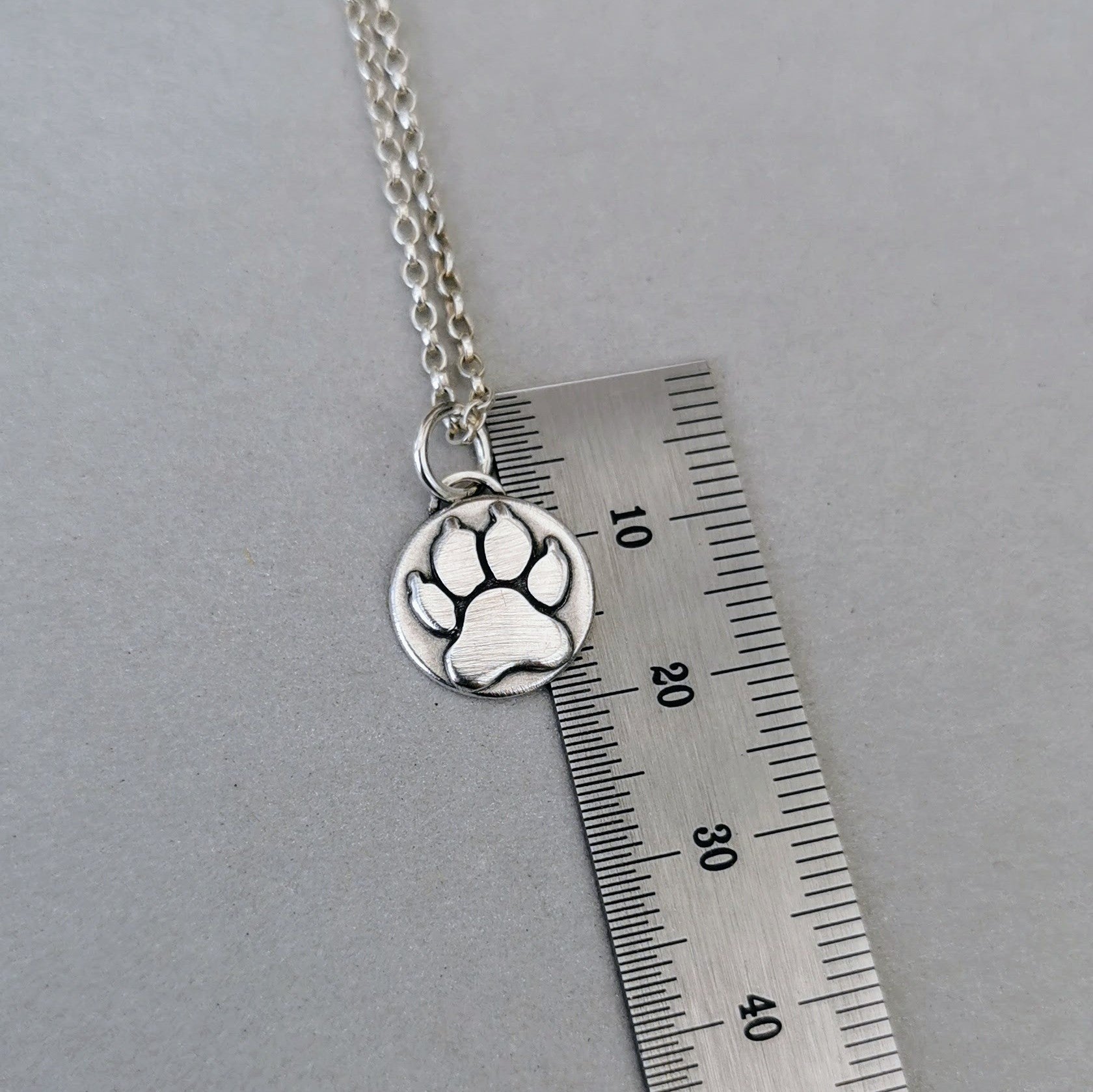 Nachhaltiger Kettenanhänger in Form einer Hundepfote, gefertigt aus recyceltem Silber, handgefertigtes Symbol für Tierliebe, personalisierbar mit Gravur.