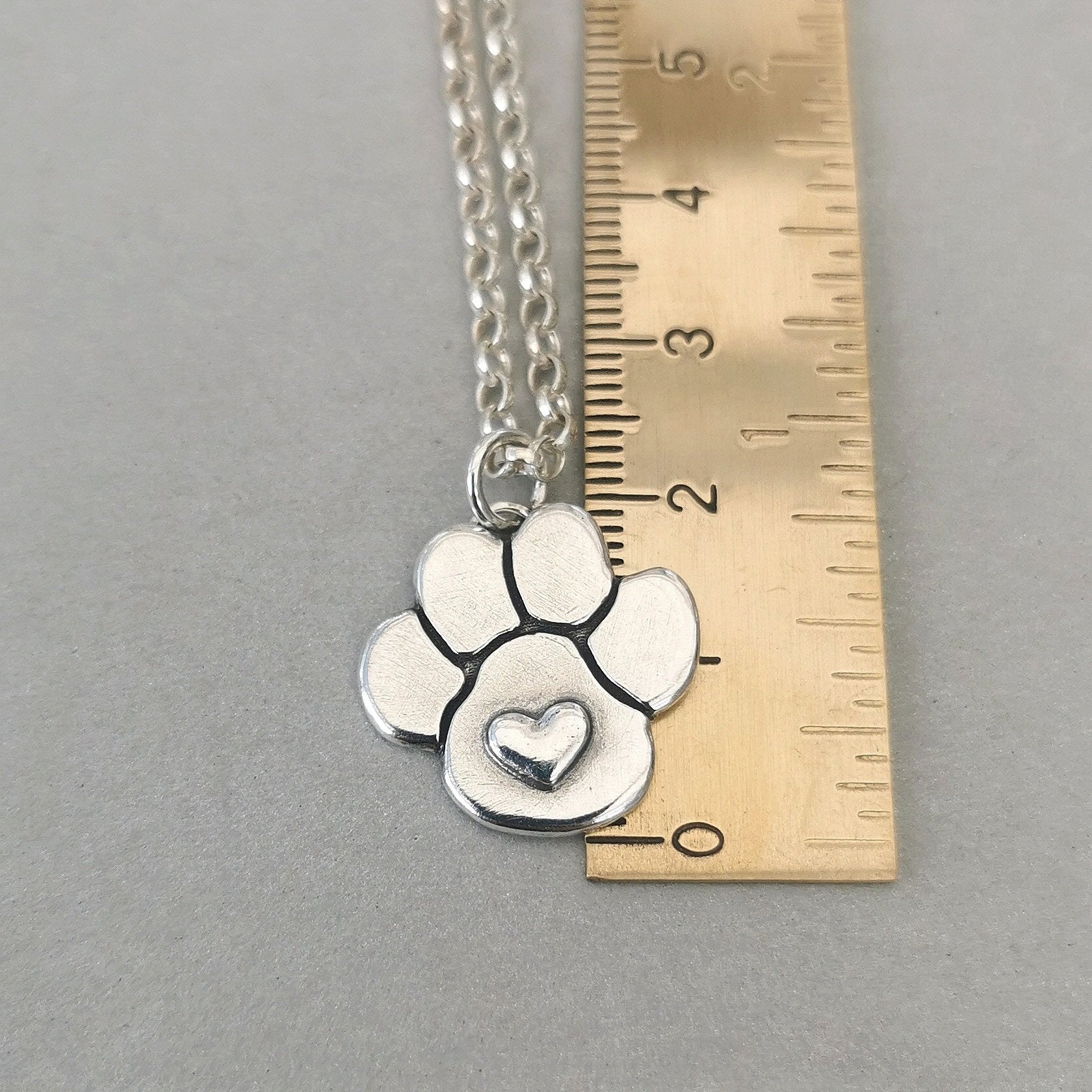 Nachhaltiger Kettenanhänger in Form einer Hundepfote mit Herz, gefertigt aus recyceltem Silber, handgefertigtes Symbol für Tierliebe.