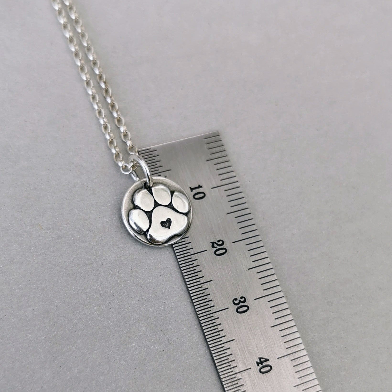 Nachhaltiger Kettenanhänger in Form einer Hundepfote mit Herz, gefertigt aus recyceltem Silber, Symbol für Pfotenliebe, handgefertigt und personalisierbar mit Gravur.