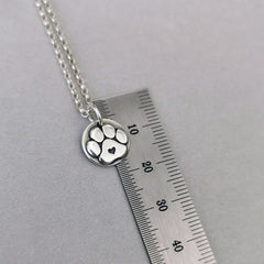 Nachhaltiger Kettenanhänger in Form einer Hundepfote mit Herz, gefertigt aus recyceltem Silber, Symbol für Pfotenliebe, handgefertigt und personalisierbar mit Gravur.