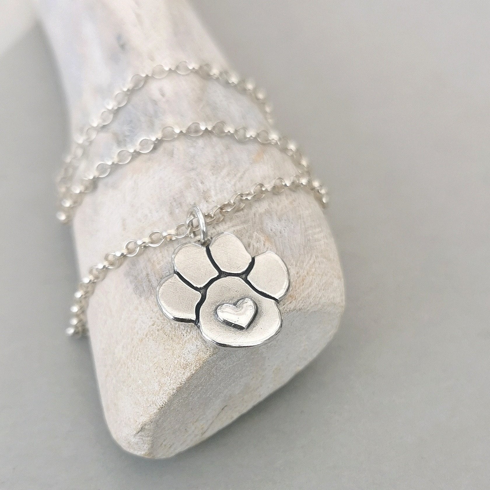 Handgefertigter Hundepfoten-Anhänger mit Herz, aus recyceltem Silber, symbolisiert die Liebe zu Tieren und Haustieren, nachhaltig hergestellt.