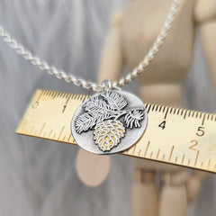 Handgefertigter Kettenanhänger „Tannenzapfen“ aus recyceltem 925er Sterlingsilber mit Teilvergoldung in 24 Karat Gelbgold. Symbol für Transformation, Geduld und inneres Wachstum – nachhaltiger Schmuck mit Bedeutung, aus Deutschland.