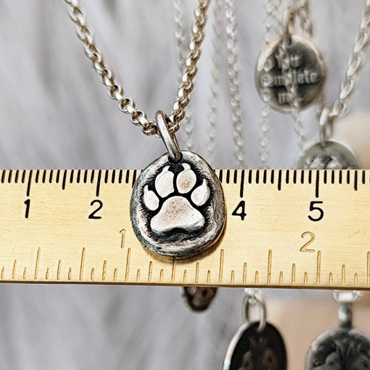 Handgefertigter Pfotenanhänger aus recyceltem 925er Silber, matt - glänzendes Finish, plastische Hundepfote mit Herz. Wahlweise mit persönlicher Gravur auf der Rückseite. Nachhaltiger Schmuck, individuell, personalisierbar, handgemacht in Deutschland – perfekt als Erinnerung für Hundeliebhaber.
