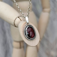 Nahaufnahme des roten, facettierten Granat - Edelsteins im recycelten Silberanhänger.