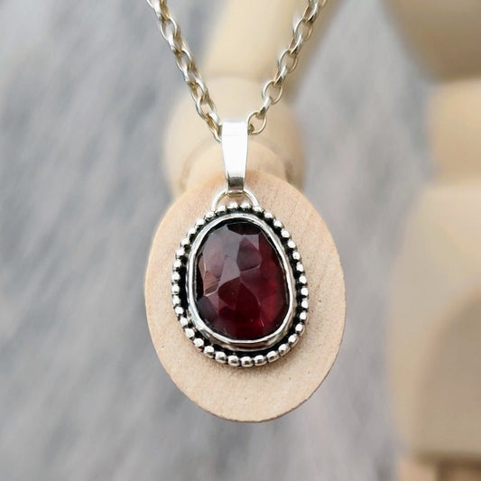 Handgefertigter Anhänger aus recyceltem Silber mit rotem Granat und Gravur auf der Rückseite.